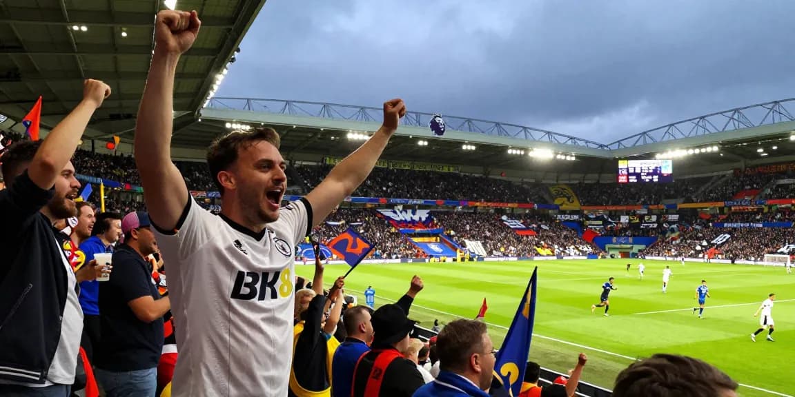 Fans celebrating BK8's sponsorship at a Premier League match with team jerseys and banners.